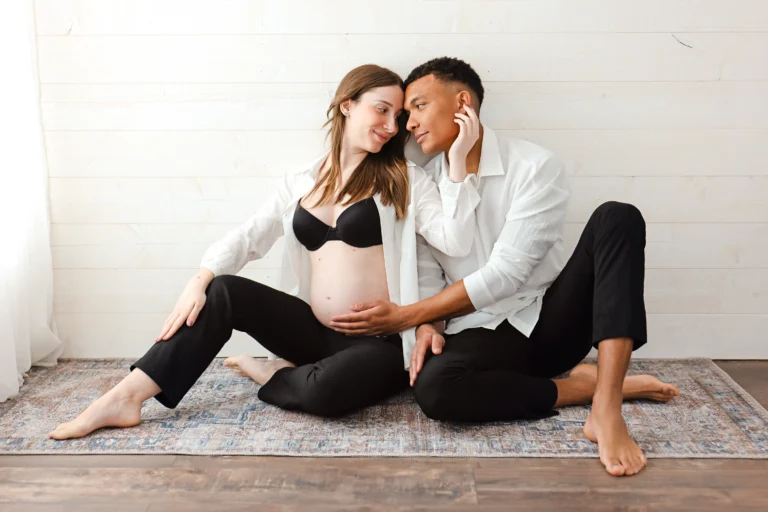 S&eacute;ance photo grossesse en couple au studio, les futurs parents assis c&ocirc;te &agrave; c&ocirc;te