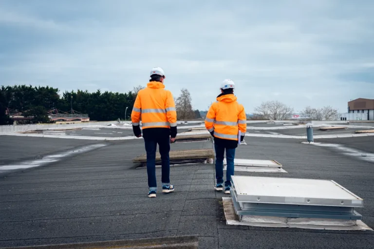 Deux techniciens d’Atelier Consulting inspectent une toiture, casque et gilet haute visibilité