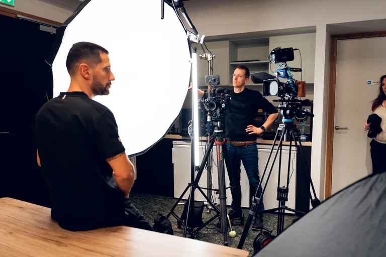 Vidéaste en backstage réglant un softbox avant un tournage en entreprise